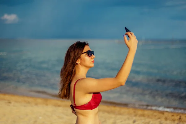 Mujer joven tomando el teléfono inteligente en la playa — Foto de Stock