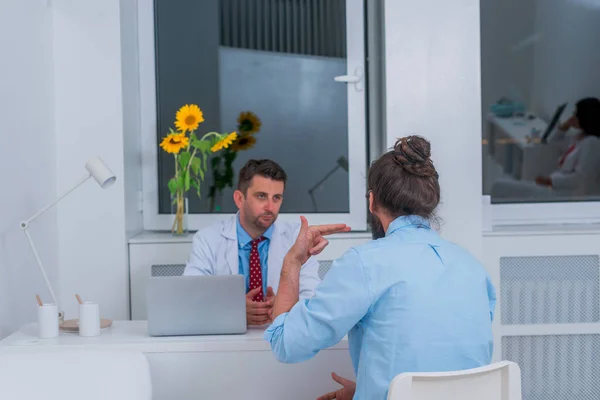 Seorang dokter sedang berbicara dengan pasien hipster di kantor dan menjelaskan — Stok Foto