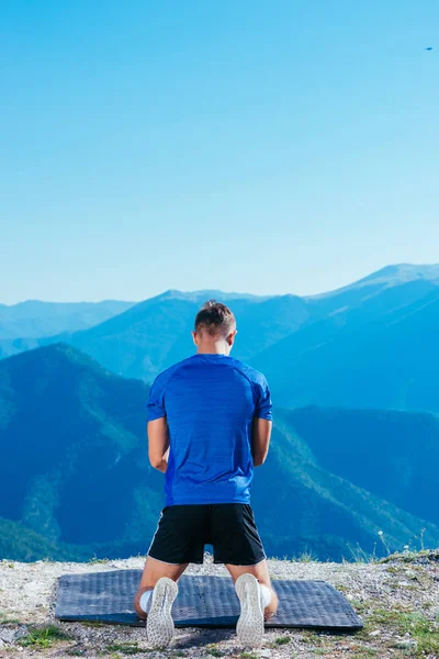 在阳光灿烂的日子里 强壮的男子运动员一边在山顶上锻炼腹肌 一边做着木板 — 图库照片