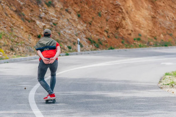 Großer fitter männlicher Longboarder, der mit seinem Longboard in der Sonne bergab fährt — Stockfoto