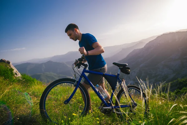 Perspektive eines fitten Mountainbikers, der sein Fahrrad bergauf schiebt — Stockfoto