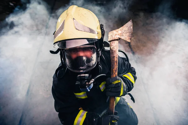 Portrait of a female firefighter while holding an axe and wearin