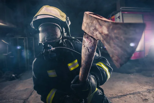 Portrait of a female firefighter while holding an axe and wearin — Stock Photo, Image