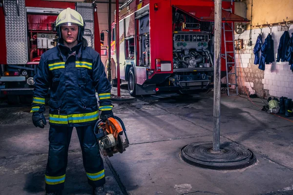Un bombero con uniforme y casco que sostiene un chaleco con fuego. —  Fotos de Stock