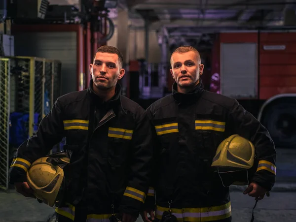 Portret dwóch młodych strażaków w mundurze stojących wewnątrz jodły — Zdjęcie stockowe