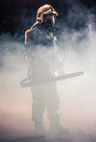 Портрет молодого пожежника, що стоїть і тримає бензопилу в — стокове фото