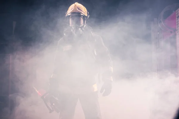 Portrait of young fireman standing and holding a chainsaw in the — Stock Photo, Image