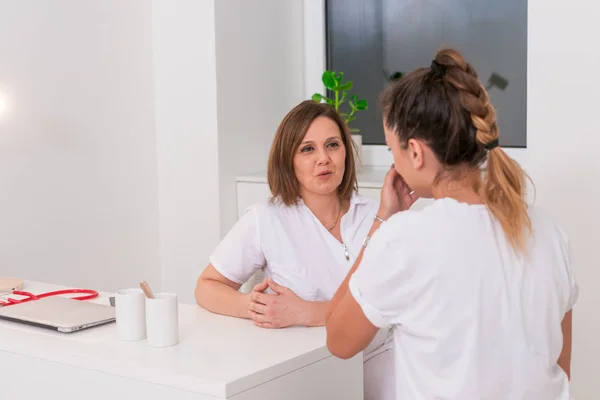 Médico feminino checando a boca de uma adolescente com um depressor . — Fotografia de Stock