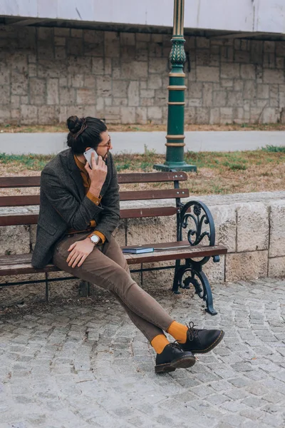 Yakışıklı Genç Bir Hippi Ahşap Bir Bankta Oturuyor Cep Telefonuyla — Stok fotoğraf