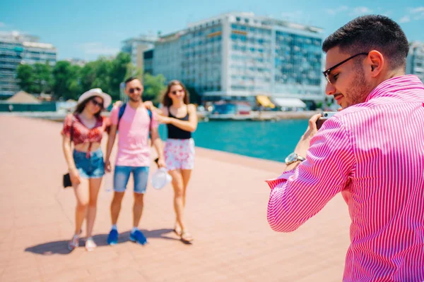 Quatro turistas tirando uma foto ao lado do mar, enquanto sendo casuall — Fotografia de Stock