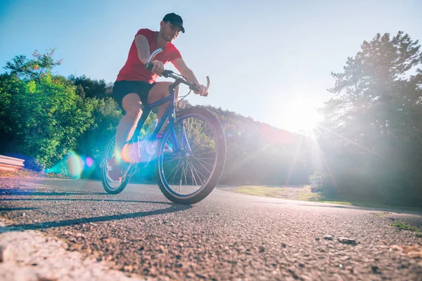 Велосипедист сидящий на велосипеде по асфальтированной дороге — стоковое фото