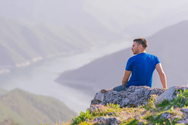 Uomo avventuroso seduto sulla cima di una montagna e godendo il be — Foto Stock