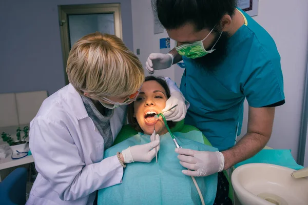 歯科で女性の歯を調べる専門的な男性と女性の歯科医 — ストック写真