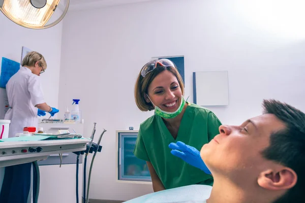 Joven Paciente Está Sentado Silla Del Dentista Una Dentista Está —  Fotos de Stock