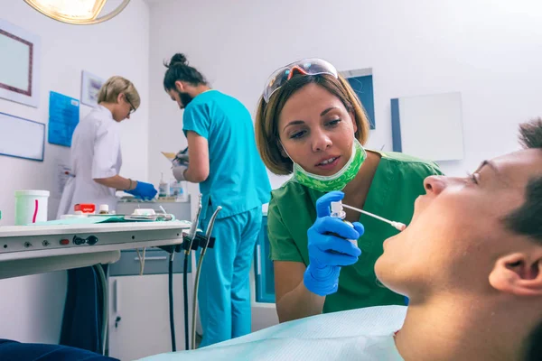 Joven Paciente Está Sentado Silla Del Dentista Una Dentista Está —  Fotos de Stock