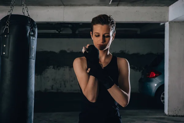 手首に黒い包帯を巻き若い強い女性の肖像画 ガレージでボクシングの準備 — ストック写真