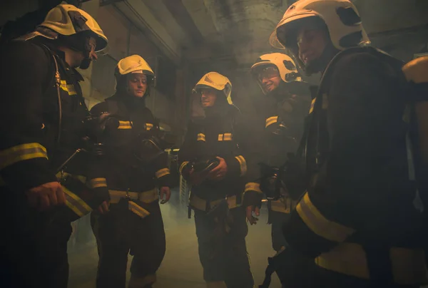 Skupina hasičů s uniformami uvnitř požární stanice přípravy — Stock fotografie