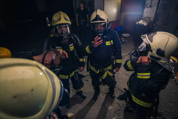 Grupo de bomberos que se encuentran dentro de la brigada de bomberos que llevan h — Foto de Stock