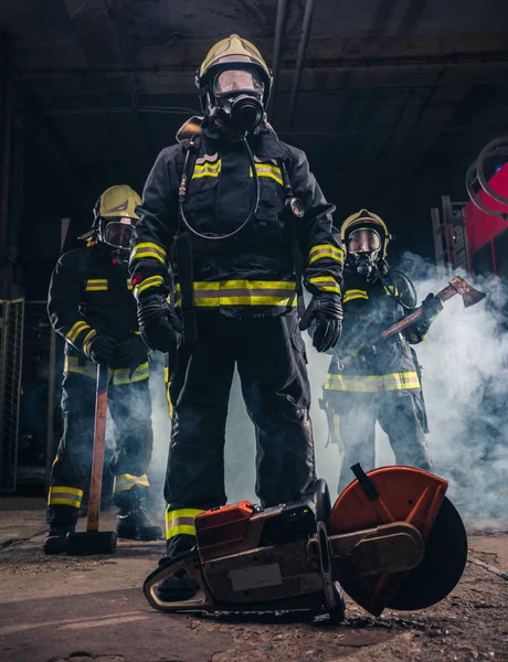 Grupo de três jovens bombeiros posando dentro do corpo de bombeiros w — Fotografia de Stock