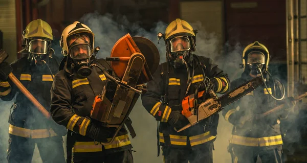 Grupa strażaków w mundurach pozujących wewnątrz straży pożarnej — Zdjęcie stockowe