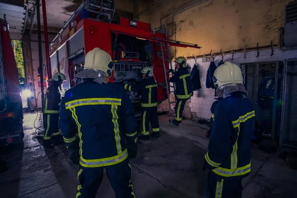 Bomberos que preparan su uniforme y el camión de bomberos de la ba —  Fotos de Stock