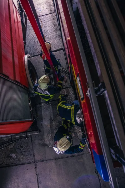 Bombeiros que verificam o motor de incêndio dentro do departamento de bombeiros — Fotografia de Stock