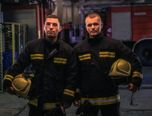 Portret dwóch młodych strażaków w mundurze stojących wewnątrz jodły — Zdjęcie stockowe