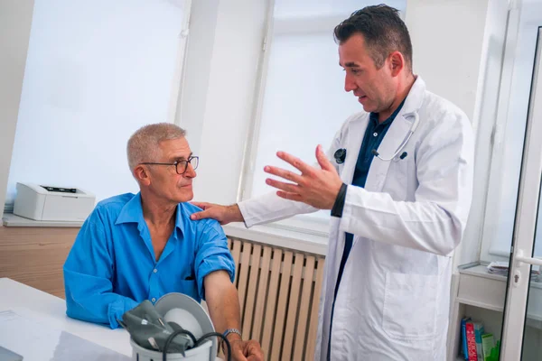 Kaukasischer Arzt mittleren Alters erklärt seinem älteren Patienten seine — Stockfoto