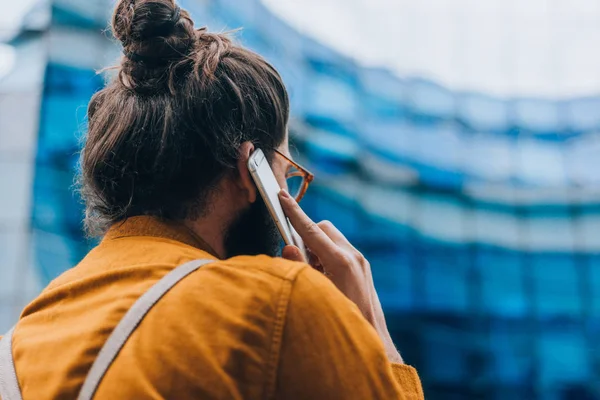 携帯電話で話す遊歩道で長い髪とひげを持つ現代の若いビジネスマン — ストック写真