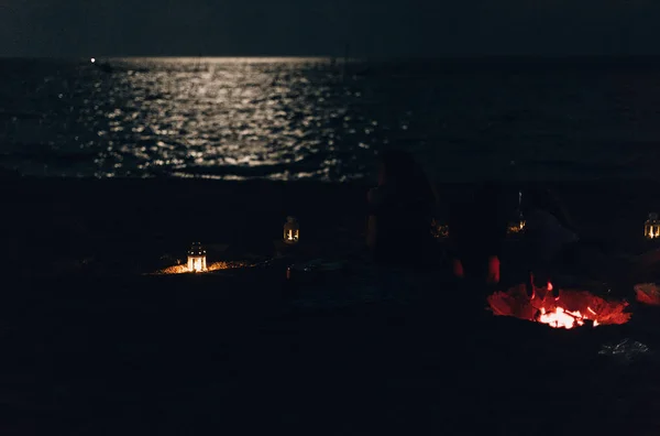 Göl kenarında şenlik ateşinin yanında oturan mutlu insanlar. gece timi — Stok fotoğraf