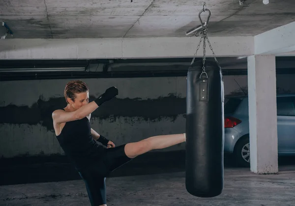 Běloška Sportovním Oblečení Černými Obvazy Kopající Boxerský Pytel Garáži — Stock fotografie