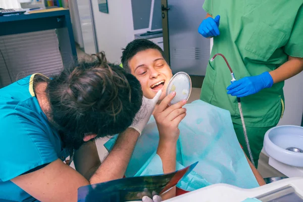 Team of dentists explaining x-ray scan picture to young boy patient