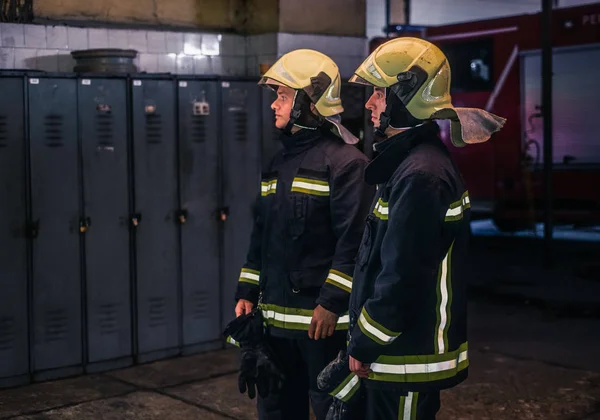 Retrato de dois jovens bombeiros em uniforme de pé dentro do abeto — Fotografia de Stock