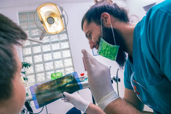 Odontólogo Masculino Mostrando Paciente Joven Sus Dientes Imagen Rayos Consultorio —  Fotos de Stock