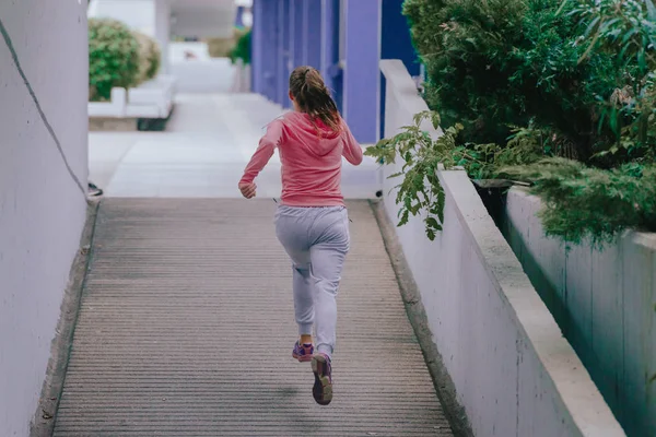 在市区跑步时穿着运动服的年轻貌美的姑娘 — 图库照片