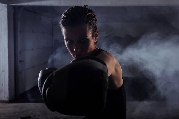 背景に白煙とボクシングの訓練を行う若い女性のシルエットの肖像画 — ストック写真