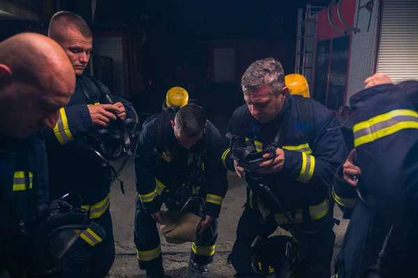 Grupo de bombeiros de pé dentro da brigada de fogo vestindo h — Fotografia de Stock