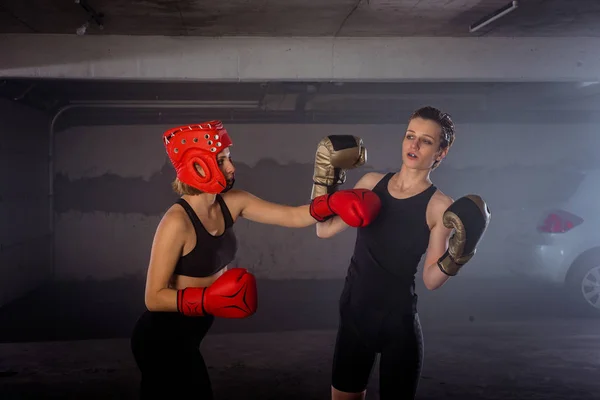 Two professional female boxers punching each other in aggressive garage boxing fight