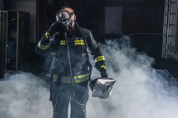 Hasič stojící sebevědomě drží helmu a nosí hasiče — Stock fotografie