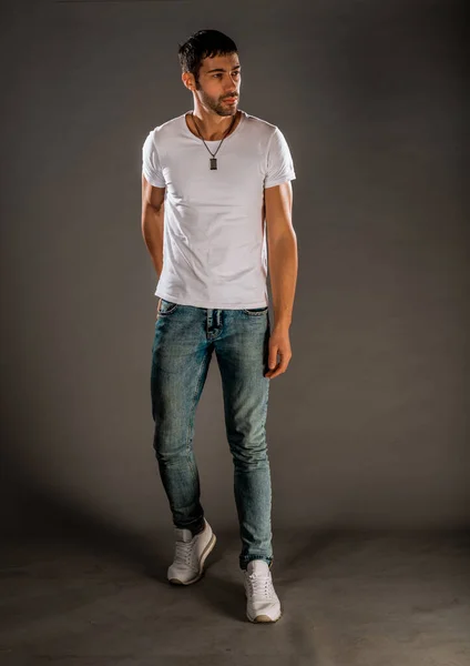 Cool handsome guy wearing stylish blue jeans, white t-shirt and sneakers