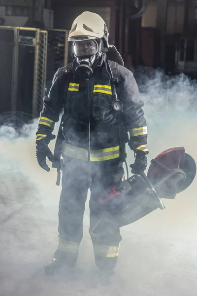 肩に鎖で支えられた防護服を着た消防士の姿が描かれている 煙と青の光で暗い背景 — ストック写真