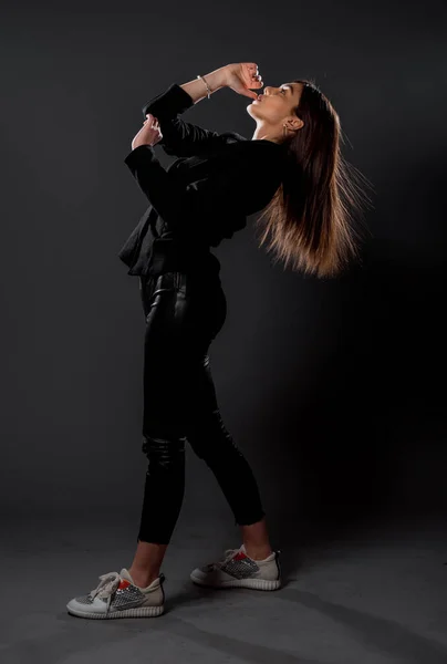 スタイリッシュなファッション女の子ポーズでトレンディーなラテックス服に暗い背景 — ストック写真