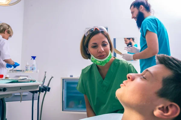 Joven Paciente Está Sentado Silla Del Dentista Una Dentista Está —  Fotos de Stock