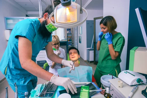 歯医者のチームは歯の道具を使って子供の歯を治療しています — ストック写真