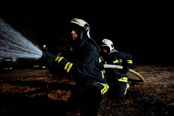 Bomberos Con Uniforme Protector Apagando Fuego Ardiente —  Fotos de Stock