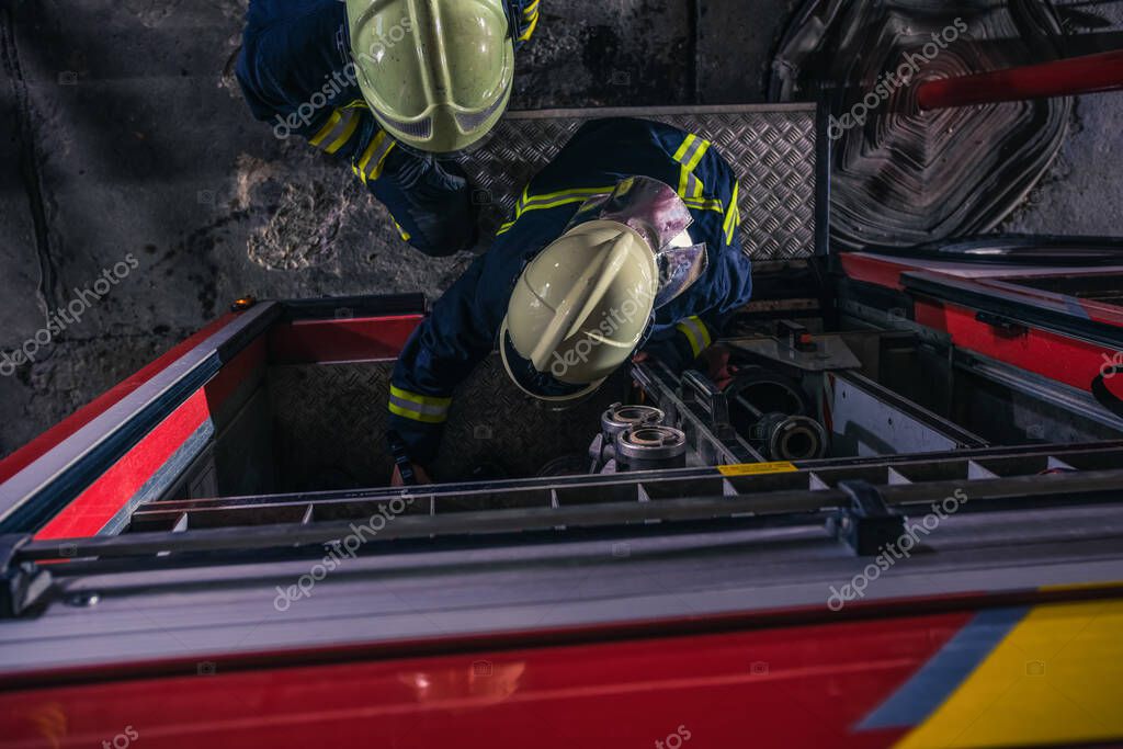 Firemen checking the fire engine inside the fire department from a bird perspective