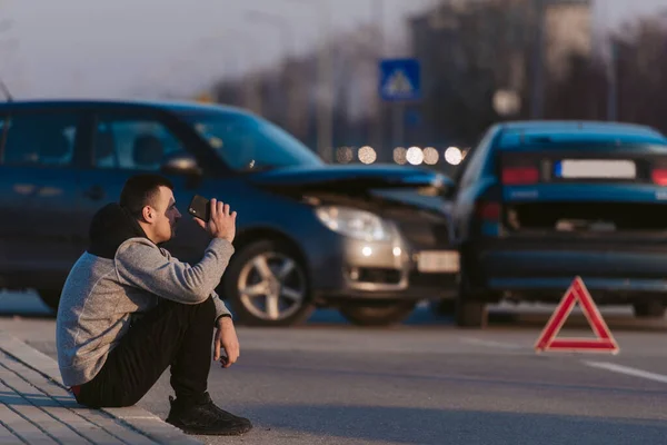 Junger Mann Sitzt Mit Handy Neben Zwei Unfallautos Auf Der — Stockfoto