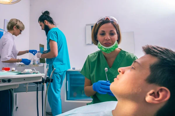 Joven Paciente Está Sentado Silla Del Dentista Una Dentista Está —  Fotos de Stock