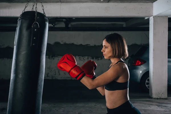 Visão Perfil Uma Jovem Forte Perfurando Saco Boxe Dentro Garagem — Fotografia de Stock