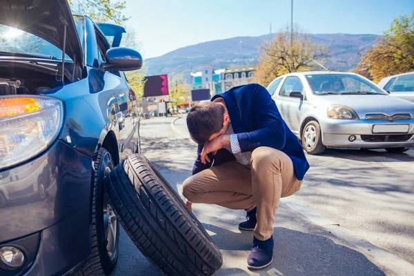 Rozzlobený Obchodník Snaží Vyměnit Píchlou Pneumatiku Klíčem Zatímco Krčí Vedle — Stock fotografie